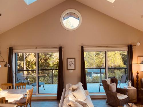 a living room with a table and chairs and windows at Haven On The Hill in Port Renfrew