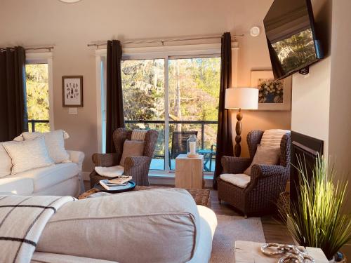 a living room with a couch and chairs and a tv at Haven On The Hill in Port Renfrew