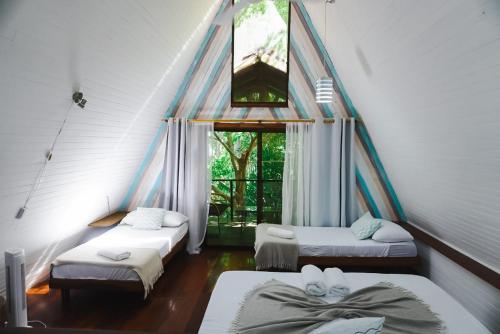 a room with three beds and a window at Calala Lodge in Cabuya