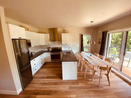 a kitchen with white cabinets and a table with chairs at Haven On The Hill in Port Renfrew