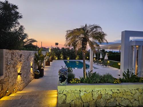 a villa with a swimming pool and a palm tree at Villa Merilusi Apartments in Fontane Bianche