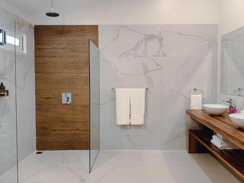 Un baño con ducha de cristal y pared de mármol. en Cloud Forest Lodge, en Monteverde