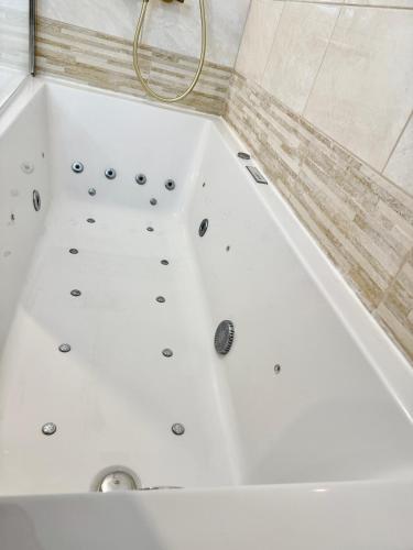 La salle de bains est pourvue d'une baignoire blanche. dans l'établissement Temple Luxe- Balnéo et Jardin, wifi, parking privé securisé, à Béziers