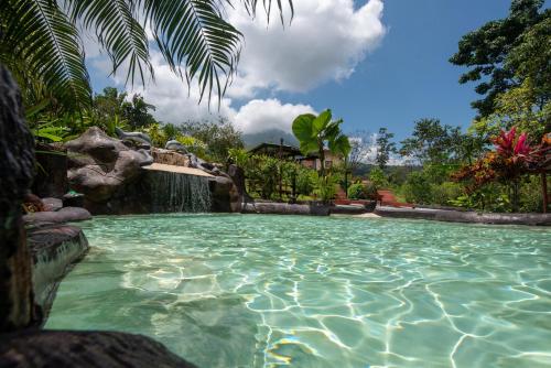 a swimming pool with a waterfall and a water slide at Hotel Dorado Hot Springs in Fortuna