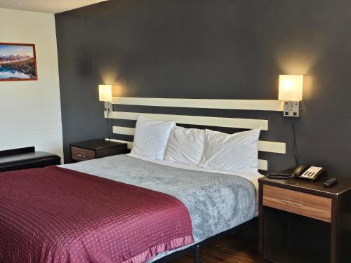 a hotel room with a bed with a red blanket and a phone at Sumner Motor Inn in Sumner