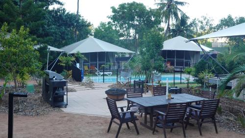 a patio with a table and chairs and umbrellas at King Safari Tent 3 in Nelly Bay
