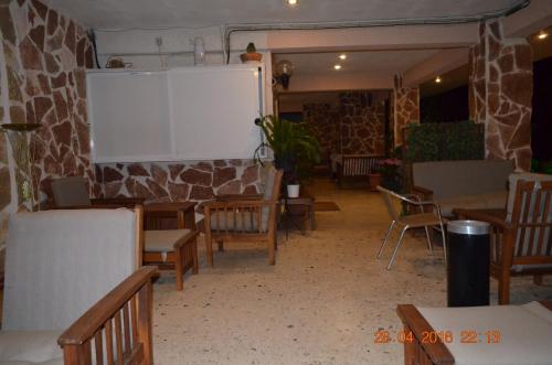 a room with tables and chairs and a stone wall at Apartments Zoumperi in Nea Makri