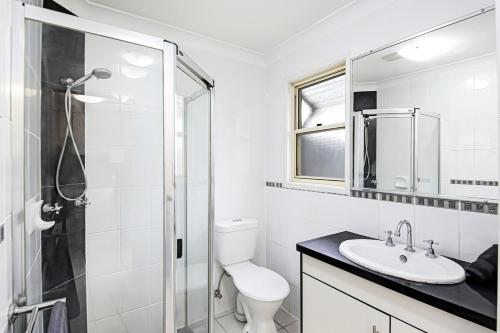 a white bathroom with a toilet and a shower at Tiny Comfy flat with Bikes in Coolum Beach
