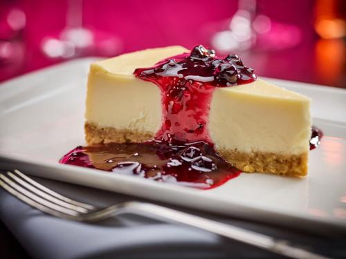 a piece of cheesecake on a plate with a fork at Mercure Northampton in Northampton