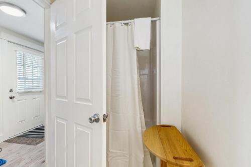 Un baño con una cortina de ducha blanca y un taburete de madera. en Lobster Trap, en Boothbay Harbor