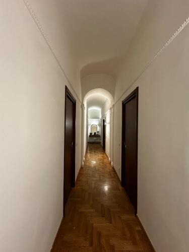 um corredor vazio com paredes brancas e pisos de madeira em The Apartment 56 em Roma