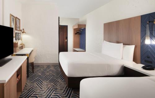 a hotel room with two beds and a television at Hotel Royer Urbana Champaign, Tapestry Collection by Hilton in Champaign