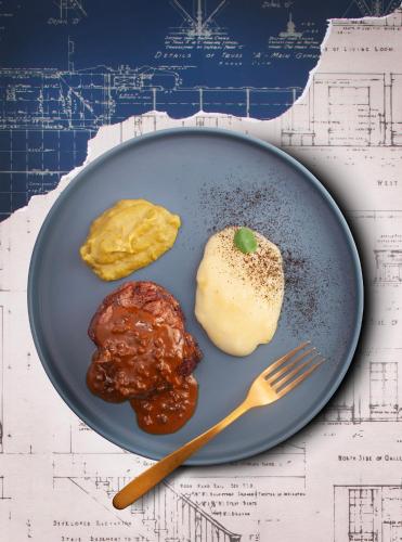 a plate of food with meat and sauce and a fork at Hotel Royer Urbana Champaign, Tapestry Collection by Hilton in Champaign