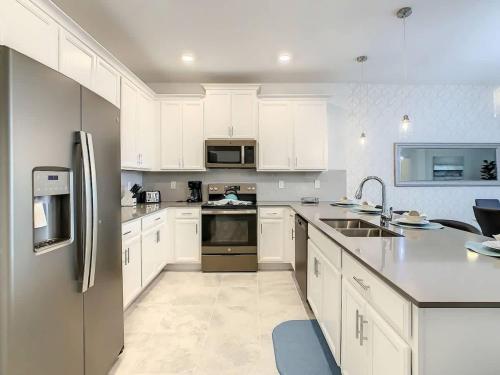 a kitchen with white cabinets and stainless steel appliances at Wonderful Disney-Themed Home in ChampionsGate Resort 15 min from Disney World with 7 pools, Club houses, Water Park, Gym, Arcades, Lazy River, Golf, and More! in Kissimmee