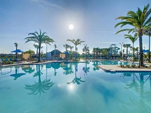 a pool at a resort with palm trees at Wonderful Disney-Themed Home in ChampionsGate Resort 15 min from Disney World with 7 pools, Club houses, Water Park, Gym, Arcades, Lazy River, Golf, and More! in Kissimmee