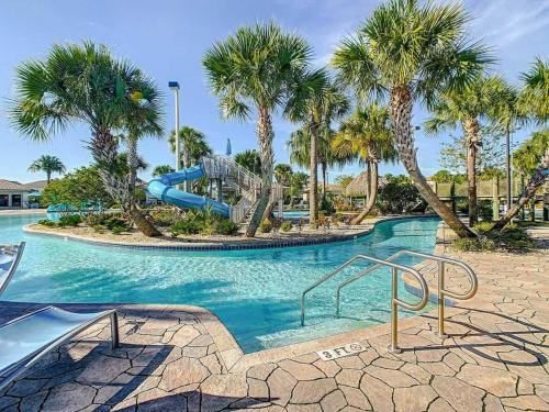 a pool with a slide in a resort with palm trees at Wonderful Disney-Themed Home in ChampionsGate Resort 15 min from Disney World with 7 pools, Club houses, Water Park, Gym, Arcades, Lazy River, Golf, and More! in Kissimmee