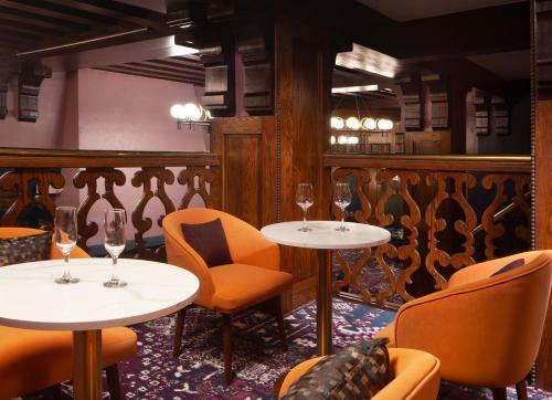 a restaurant with two tables and chairs and wine glasses at Hotel Royer Urbana Champaign, Tapestry Collection by Hilton in Champaign