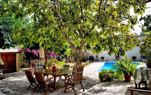 una mesa y sillas bajo un árbol junto a una piscina en Narkissos Villa, en Kallepia
