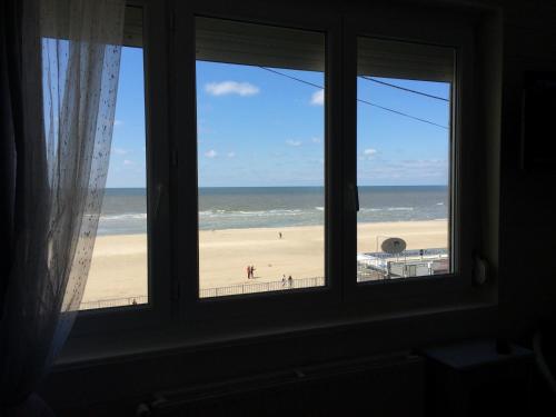 a window with a view of a beach and the ocean at Les Chambres d'Hôtes de la Mer in Merlimont