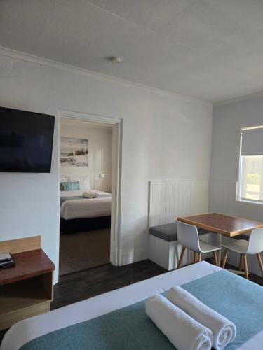 a hotel room with a bed and a desk and a table at Araluen Motor Lodge in Batemans Bay