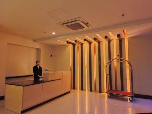 Un hombre de pie en un mostrador de recepción en un vestíbulo en Affordable Hotels Condotel Here Naia 1 ,2,3 And 4, en Manila