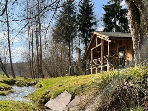 a wooden house on a hill next to a river at La Linotte in Arville