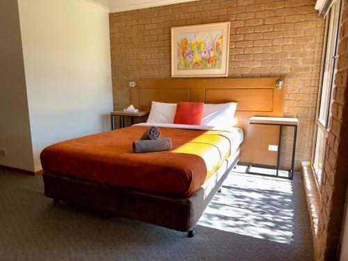 a bedroom with a large bed with a brick wall at Darling Junction Motor Inn in Wentworth