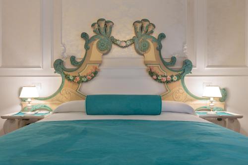 a bed with a green and white headboard and two lamps at Guelphs Apartments in Verona