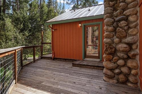 a small red cabin with a wooden deck at Cub House- Remodeled cabin INSIDE Yosemite with new hot tub and more in North Wawona