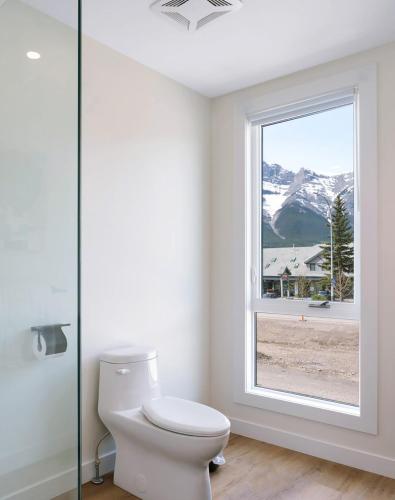 a bathroom with a toilet and a window at Raven's Peak 105 - Ultra luxe Mountain Retreat in Canmore