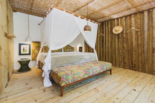 a bedroom with a bed with a mosquito net at Vila Botanika Caraíva in Caraíva
