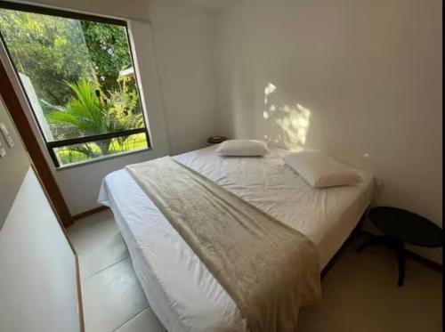 a bedroom with a large bed and a window at Village itacimirim completo in Camacari