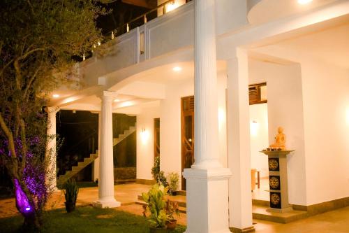 a large white house with columns and lights at Serene Villa Airport Transit in Katunayake