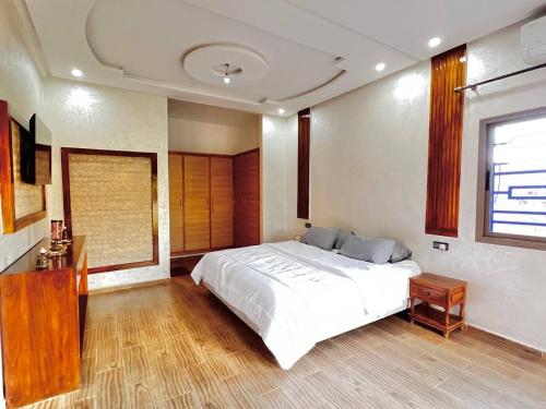 a bedroom with a large white bed and a window at Villa - Dar Tura in Tikoutar