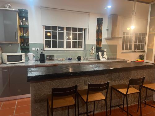 a kitchen with a bar with chairs and a microwave at Quinta do Lameiro Maceira in Seia