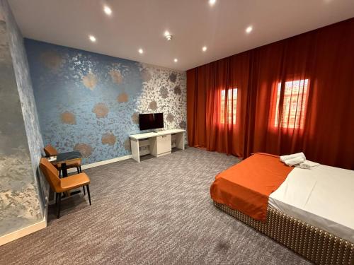 a bedroom with a bed and a desk and a television at Black Mont İnn Hotel in Baku