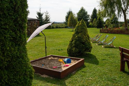 a sandbox with an umbrella in a garden at Agroturystyka u Janeckich in Czarny Młyn