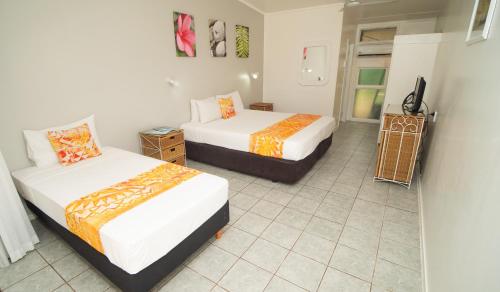 a bedroom with two beds and a tiled floor at Club Raro Resort- Adults Only in Rarotonga