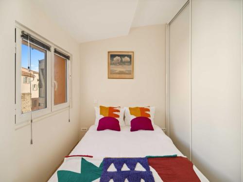 - une chambre avec un lit doté d'oreillers colorés et d'une fenêtre dans l'établissement Charming apartment - 1BR- Saint-Tropez, à Saint-Tropez