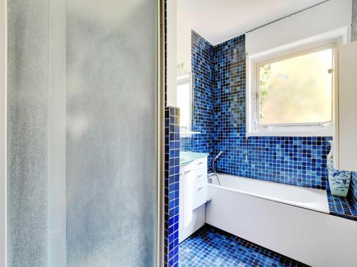 La salle de bains est pourvue de carrelage bleu, d'une baignoire et d'une fenêtre. dans l'établissement Charming duplex - 4BR-5P- Boulogne-Billancourt, à Boulogne-Billancourt