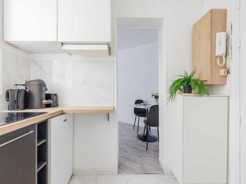 une cuisine avec des armoires blanches et une table dans l'établissement Intimate studio - 2P - Vincennes Lac Saint-Mandé, à Vincennes