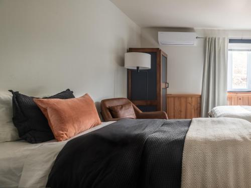 a bedroom with a bed with pillows and a chair at Le Relais des Hautes Gorges in Saint Aime Des Lacs