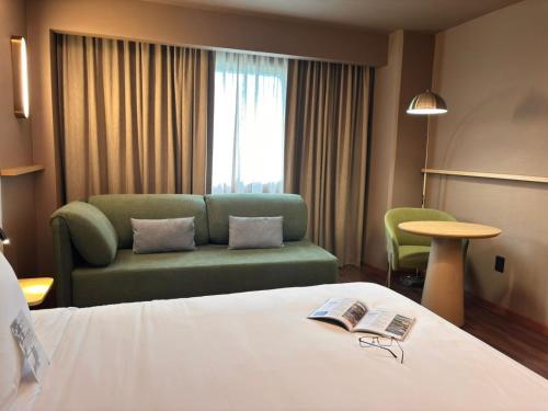 a hotel room with a bed and a couch at Novotel Monterrey Valle in Monterrey