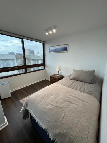 a bedroom with a bed and a large window at Céntrico Departamento Dúplex a pasos del Metro in Santiago