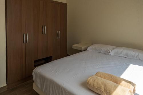 a bedroom with a white bed with a wooden cabinet at Ecohouse Cieneguilla in Pachacamac