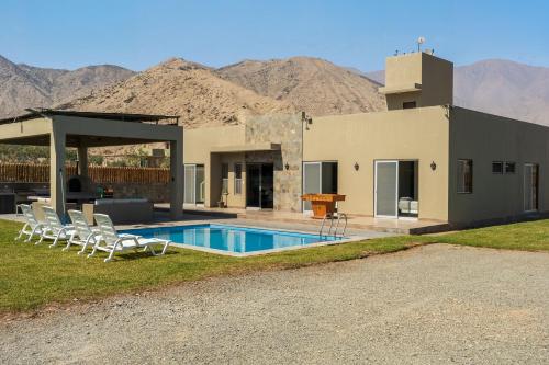 a house with a swimming pool with mountains in the background at Ecohouse Cieneguilla in Pachacamac