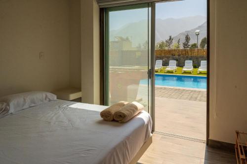 a bed with a towel on it next to a sliding glass door at Ecohouse Cieneguilla in Pachacamac