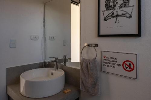 a bathroom with a sink and a sign on the wall at Ecohouse Cieneguilla in Pachacamac