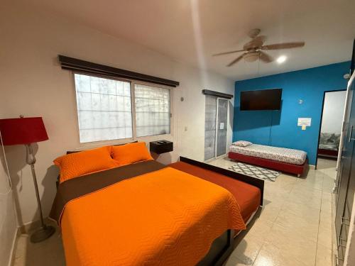 a bedroom with an orange bed and blue walls at Estudio Luxury Room in Chetumal