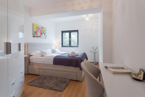 a white bedroom with a bed and a desk at Apartment Navigatio with parking in Dubrovnik
